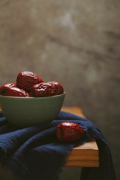 a bowl full of strawberries sitting on top of a wooden table next to a blue towel