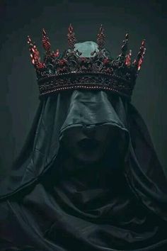 a woman wearing a black veil with a crown on her head and red lights in the dark