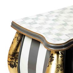 an artisticly designed table with black and white stripes on the top, gold accents