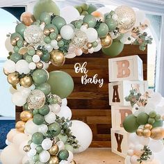 an arch made out of balloons and greenery with the words oh baby above it