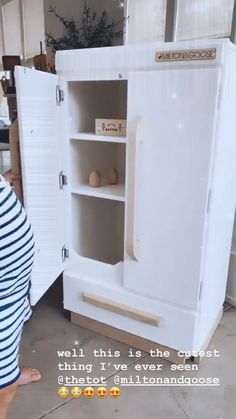 a pregnant woman standing in front of a white cabinet that has an egg inside it