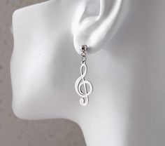 a white mannequin head with a musical note earring on top of it