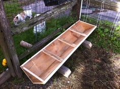 a wooden bench sitting in the grass next to a fence and some dogs behind it