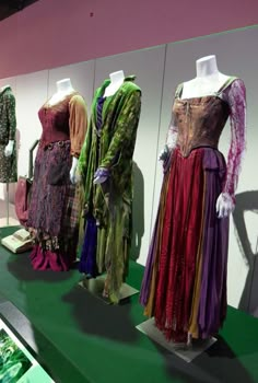 several dresses are on display in front of a green floor and white walls with pink trim