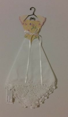 a white dress hanging on a wall next to a hanger with an image of a baby