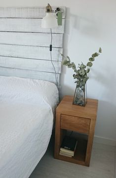 a bed with a white bedspread next to a wooden night stand