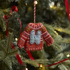 an ornament hanging from a christmas tree decorated with red and white knitted mittens