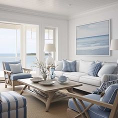 a living room filled with blue and white furniture next to an ocean side wall mounted painting