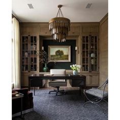 a home office with wood paneling and chandelier