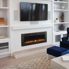 a living room with a large television mounted on the wall and a fire place in front of it