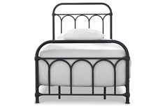 an iron bed frame with white sheets and pillows on the headboard, against a white background