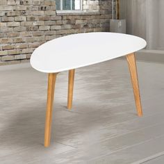 a white table with wooden legs in front of a brick wall