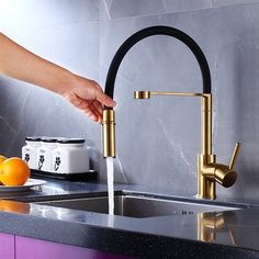 a person is washing their hands under a faucet in a kitchen sink with oranges on the counter