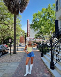 a woman in short shorts and white boots posing for the camera