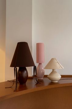 three lamps are sitting on a table next to each other and one lamp has a pink shade