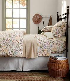 a bedroom with a bed, basket and hat on the headboard in front of a window