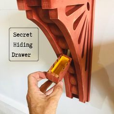 a hand is holding a piece of wood with the words secret hiding drawer on it