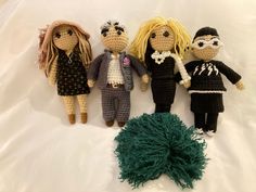 three crocheted dolls and a ball of yarn on a white sheet with a green pom - pom