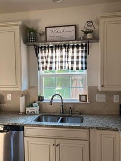 a kitchen with white cabinets and black and white checkered valance on the window