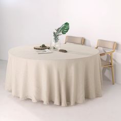 a round table with two chairs and a plant in a vase on the table top