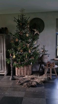 a small christmas tree in a basket next to a fireplace