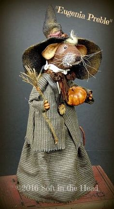 a mouse dressed in a dress and hat with a pumpkin on it's head