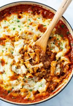 a skillet filled with pasta and meat covered in sauce, cheese and parsley