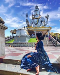 a woman sitting on steps in front of a statue