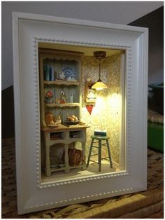 a miniature dollhouse is shown in a white frame with an open door to the kitchen