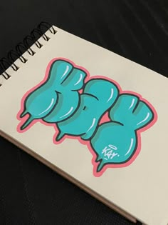 a spiral notebook with blue and pink graffiti on the cover, sitting on a black surface