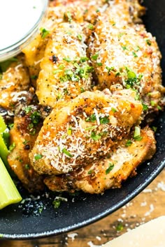 chicken wings with parmesan cheese and celery on a black platter