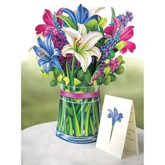 a painting of flowers in a vase next to a greeting card on a white table