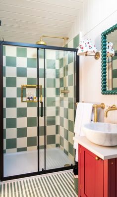 a bathroom with green and white checkered walls, a pedestal sink, and a walk in shower