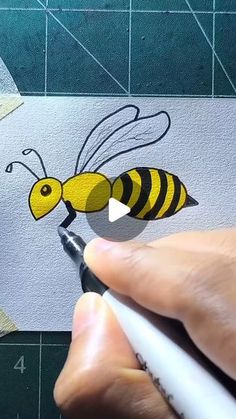 someone is drawing a bee on the paper