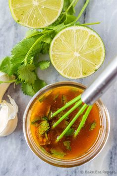 an overhead view of a bowl of soup with limes, garlic and cilantro