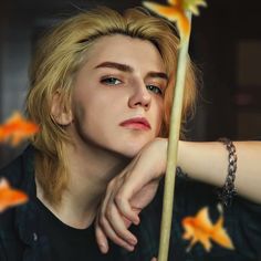 a young man with blond hair holding a stick