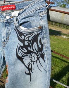 a pair of blue jean shorts with black and white designs on them, in front of a fence