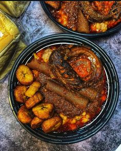 two black bowls filled with food on top of a table