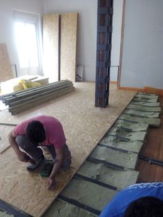 a man working on the floor in a room with unfinished walls and boards around him