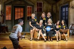 a group of women sitting next to each other on a wooden floor in front of a man