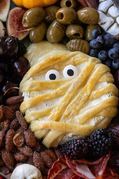 a close up of a plate of food with fruit and vegetables in the shape of a face