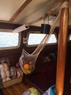 a hammock hanging from the side of a boat filled with fruits and vegetables