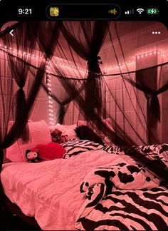 a bed with pink and black comforter in a room that has lights strung from the ceiling