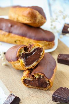 chocolate covered pastries sitting on top of a cutting board next to pieces of bread