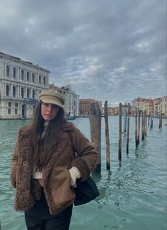 a woman is standing in the water next to a pole and building with a clock on it