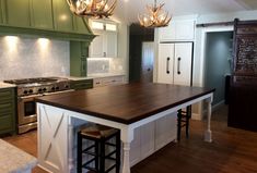 a large kitchen with green cabinets and white counter tops, an island in the middle