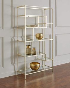 a metal shelf with three bowls and two vases on it in front of a white wall