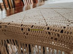 a crocheted table cloth with fringes on it sitting on top of a wooden table