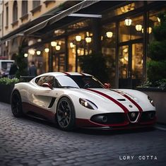 a white and red sports car parked in front of a building with lights on it