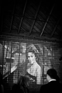 people standing in front of a brick wall with a large painting on it's side